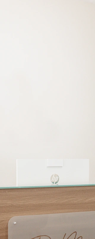 Modern reception desk in a bright, minimalistic office with a computer, hand sanitizer, and a plant near a door labeled "PRIVATE".