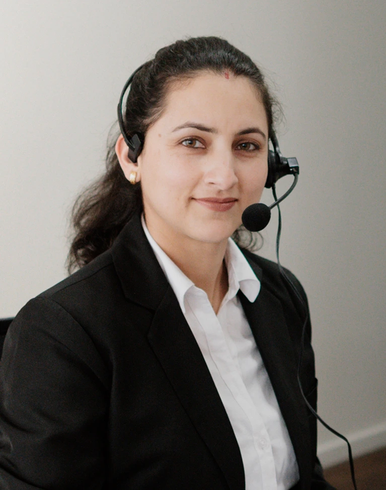 Friendly female customer service representative wearing a headset, sitting at a desk in a professional office setting.